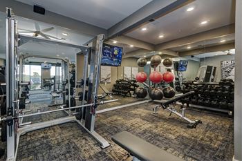 A gym with weights and cardio equipment and a mirror